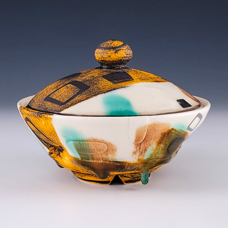 Lidded ceramic jar with mustard and teal surface decoration